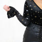 Model wearing Space Oddity Glitter Velvet Bodysuit, a Black Velvet with Silver and Gold Glitter Bodysuit, with Front button popper fastening with plunge neck and flared cuff