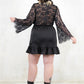 Model wearing Edge of Seventeen Mini Dress, a luxe black satin dress with a sheer lace back and eyelash lace flared sleeves