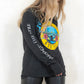 Model wearing Guns N Roses Hollywood Tour Tee - Charcoal Long Sleeve Band Tee with Yellow and Blue Guns N Roses Logo on front and tour dates on back
